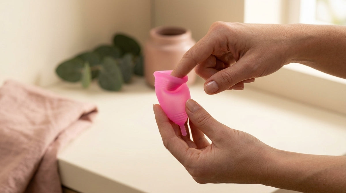 Roke prikazujejo pregib rožnate menstrualne skodelice Floena