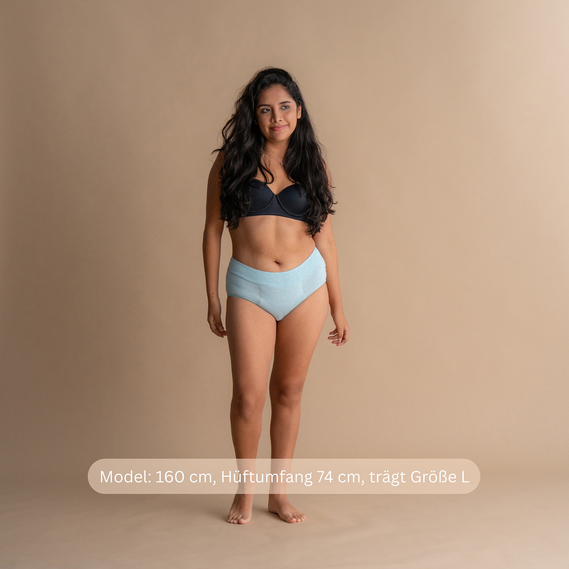 Model 160 cm groß, Hüftumfang 74 cm, trägt Größe L im hellblauen Leakproof Bamboo High Waist Brief High-Waist-Periodenslip vor beigefarbenem Hintergrund