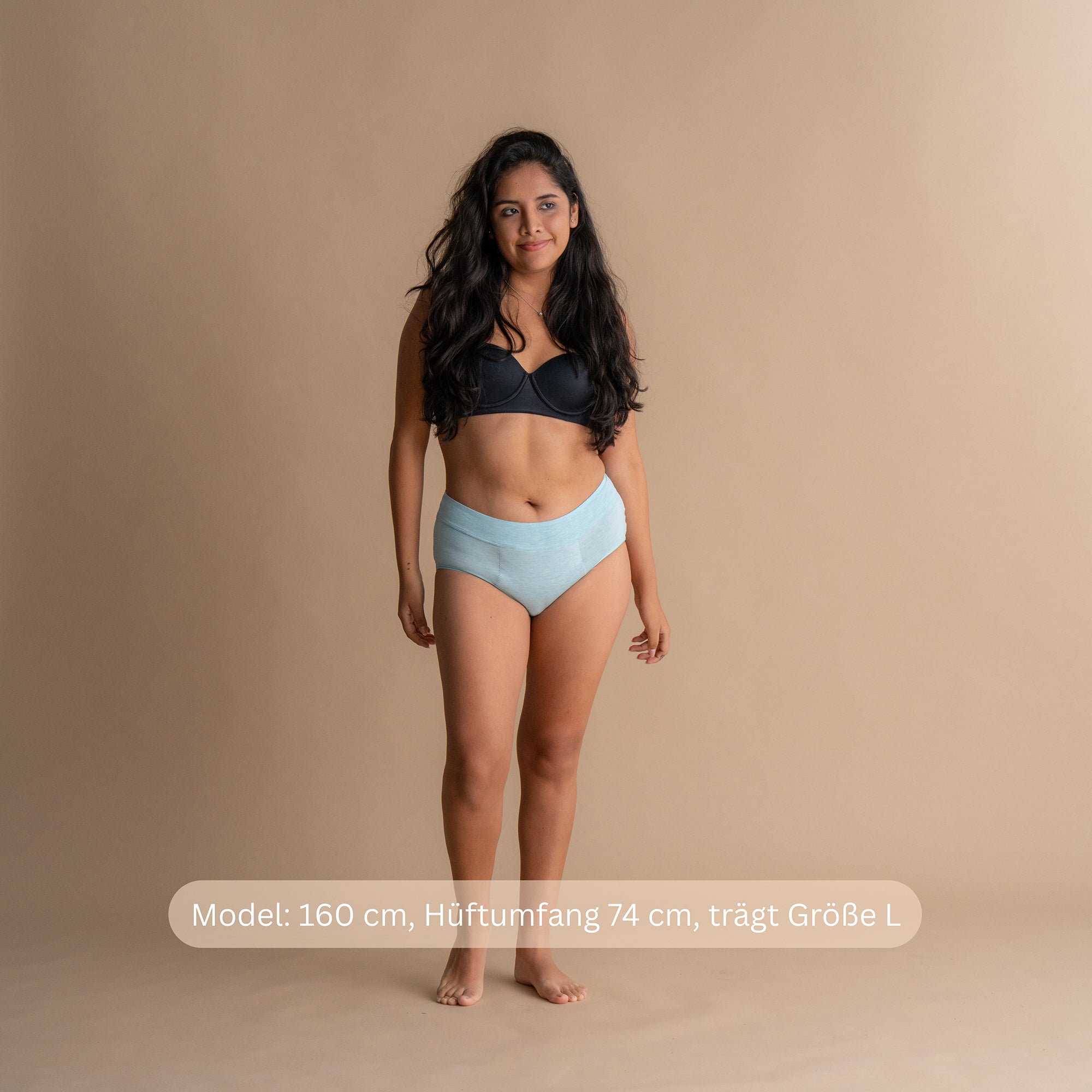 Model 160 cm groß, Hüftumfang 74 cm, trägt Größe L im hellblauen Leakproof Bamboo High Waist Brief High-Waist-Periodenslip vor beigefarbenem Hintergrund