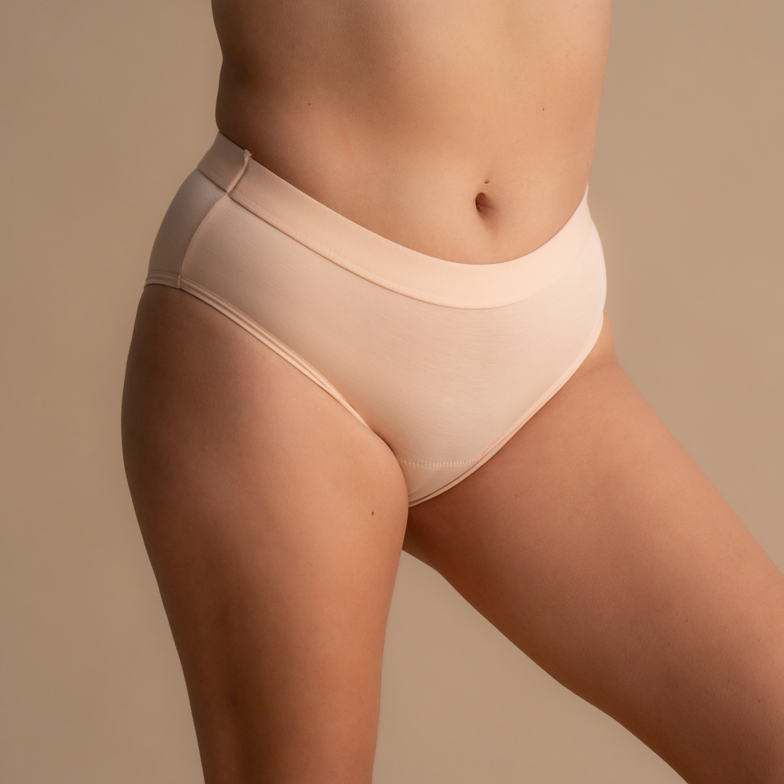 Close-up view of the side of the model wearing the Leakproof Everyday Bamboo Bikini in light pink. The design features a smooth waistband for added comfort, showcasing the soft fabric of the underwear in a natural, minimalistic style.