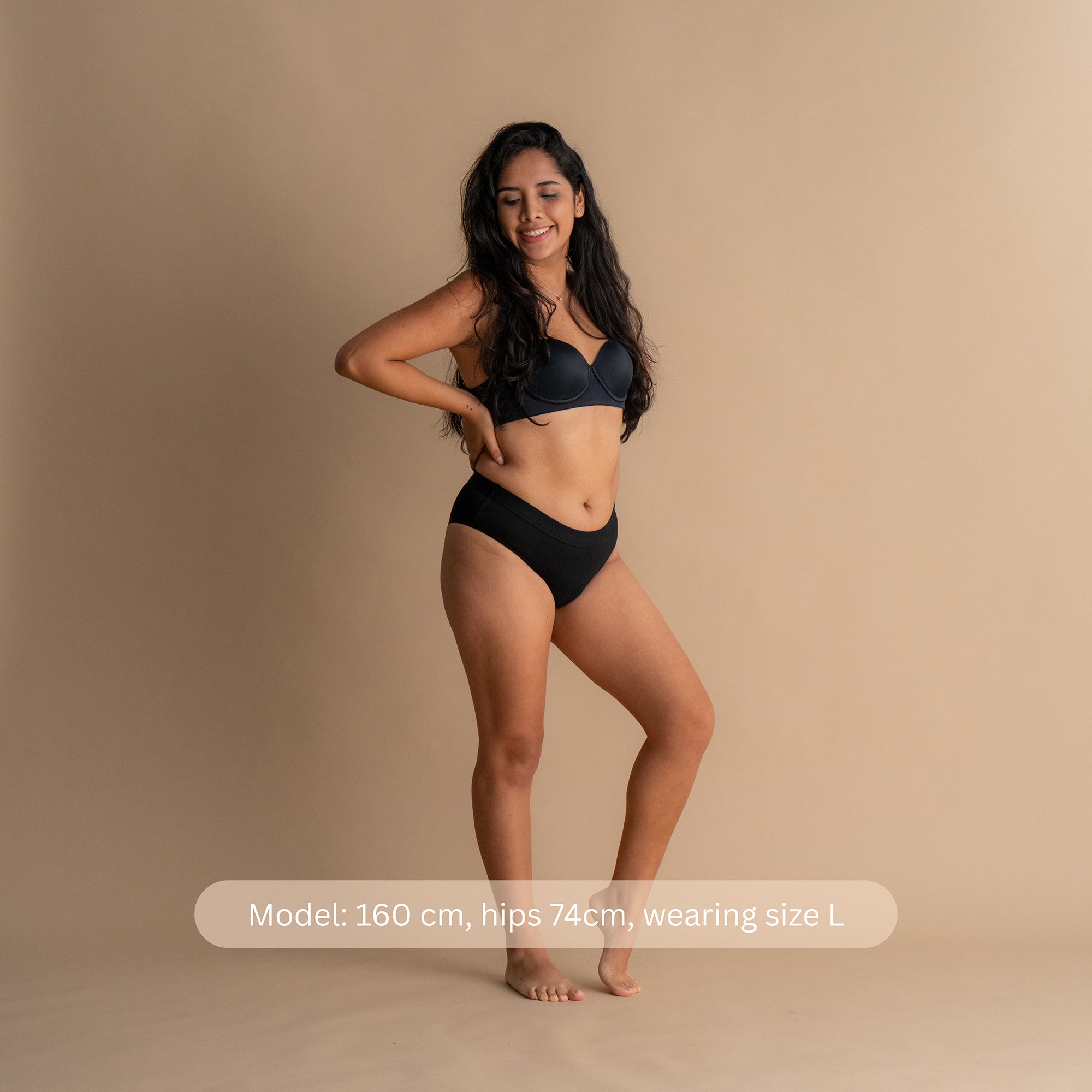 Front view of a model wearing the Leakproof Everyday Bamboo Bikini in black. The model is 160 cm tall with hips measuring 74 cm, and is wearing a size L. The brief is designed for comfort and reliable protection with a smooth waistband.