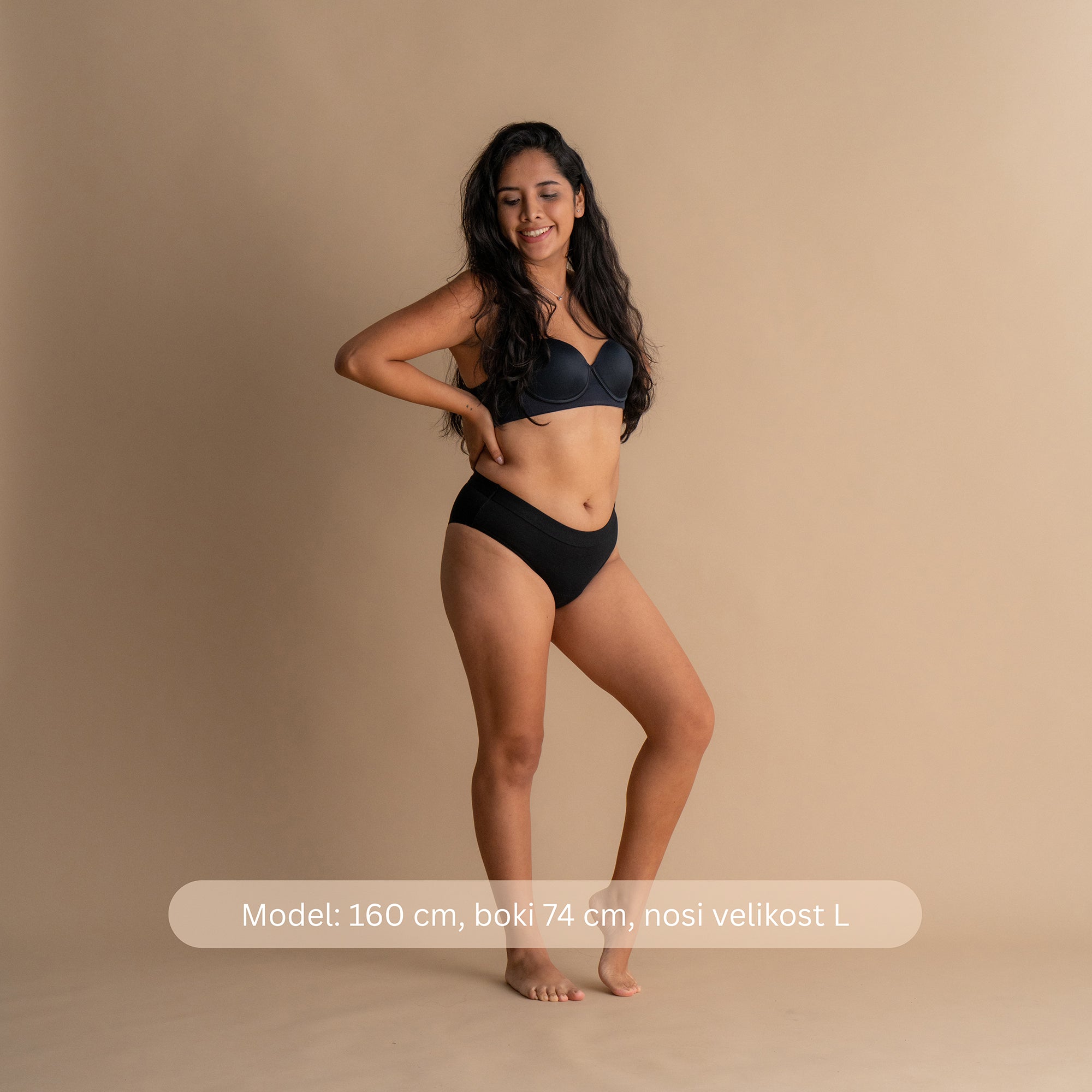 Celotni pogled spredaj na modelu, ki nosi Leakproof Everyday Bamboo Bikini v črni barvi. Model je visok 160 cm, bokov 74 cm, nosi velikost L. Bikini ponuja dihajočo bambusovo tkanino za vsakodnevno udobje in lahkotno zaščito.