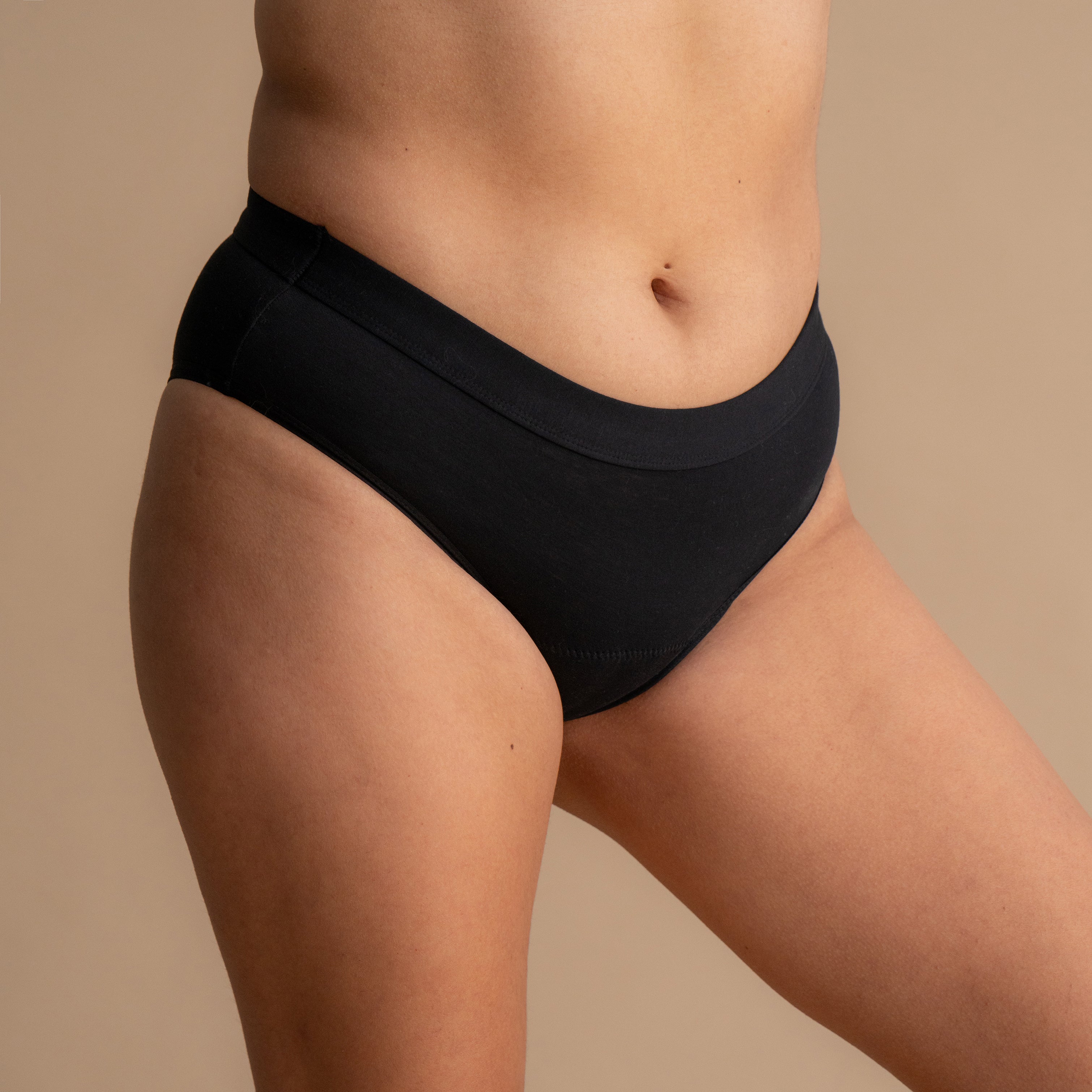 Vollständige Seitenansicht des Modells, das den Leakproof Everyday Bamboo Bikini in Schwarz trägt, mit komfortablem, atmungsaktivem Stoff und einem glatten Bunddesign. Das Modell steht natürlich und demonstriert die Passform und Abdeckung des Bikinis.