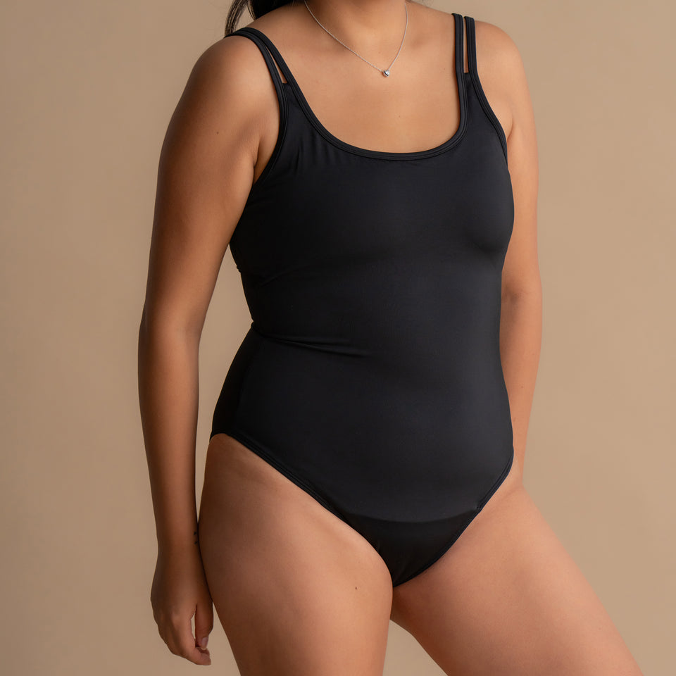Full-body view of a woman wearing the black Floena Leakproof Period One-Piece Swimsuit period swimwear with built-in leak protection