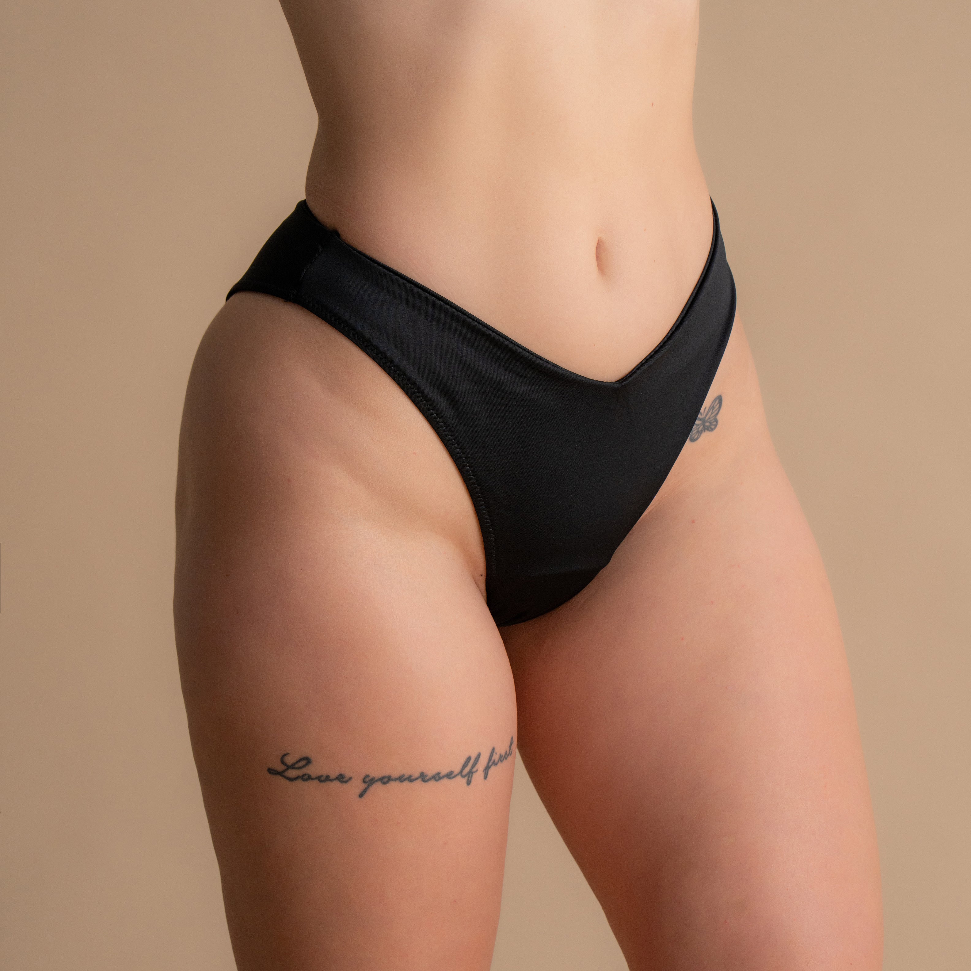 Nahaufnahme der schwarzen Leakproof Period Swim Bikini Bottom mit einem schmeichelhaften V-Ausschnitt und einem hohen Beinausschnitt für eine stilvolle, bequeme Passform. Der Bottom bietet diskrete, eingebaute Schutz und ist perfekt für das Schwimmen mit Vertrauen.