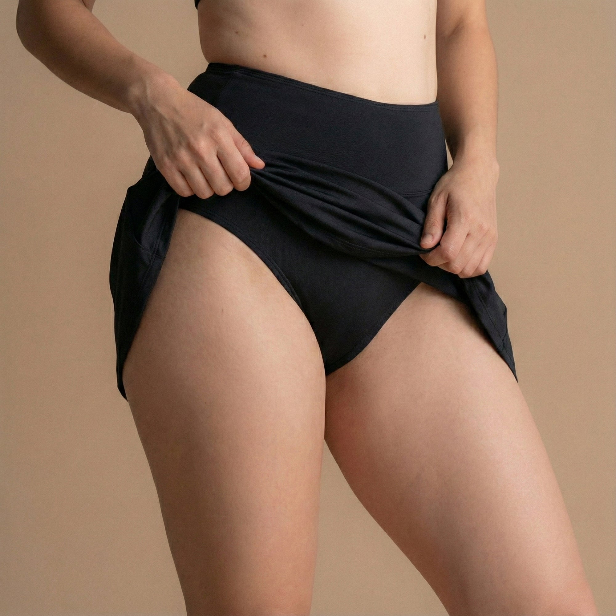 Front Side view of a model wearing the Leakproof Period Swim Skirt, highlighting the flattering design and built-in period protection. The skirt provides comfort and discretion, with a high-waisted cut and water-repellent fabric that locks leaks in while you move freely.