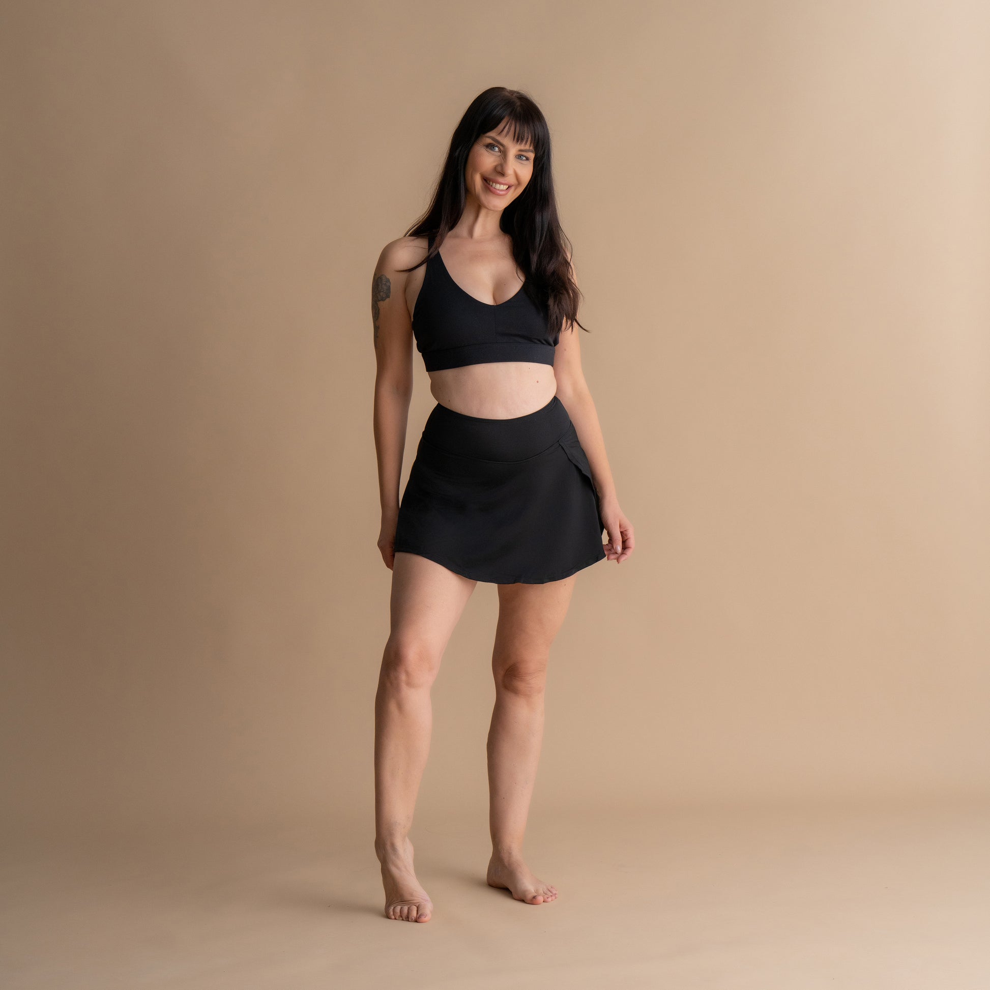 full body Front View of a model wearing the Leakproof Period Swim Skirt paired with a matching bikini top. The swim skirt provides discreet, built-in period protection while offering a flattering and comfortable design for swimming, sunbathing, or strolling.