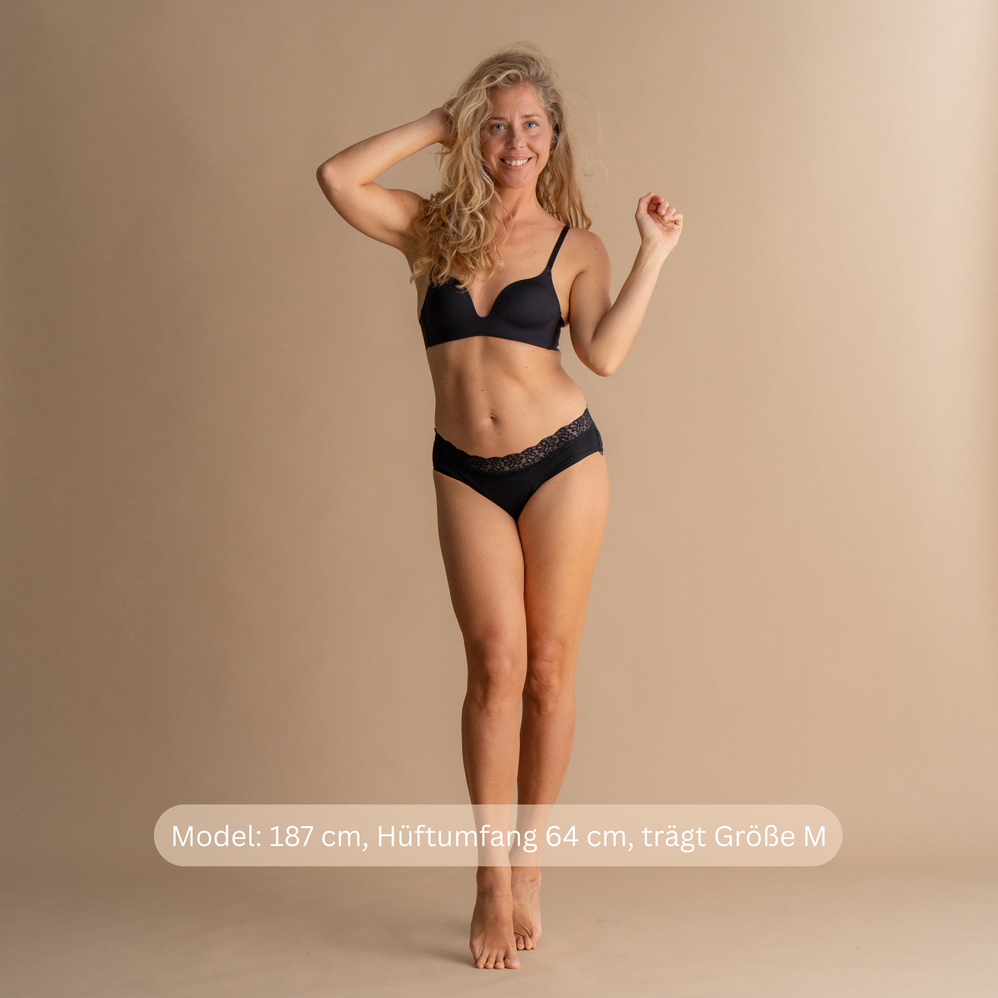Vollkörperansicht eines Modells, das die Leakproof Soft Cotton Brief in Schwarz trägt, mit zartem Spitzenmuster und bequemem Sitz. Das Modell ist 187 cm groß, hat Hüftumfang 64 cm und trägt Größe M.