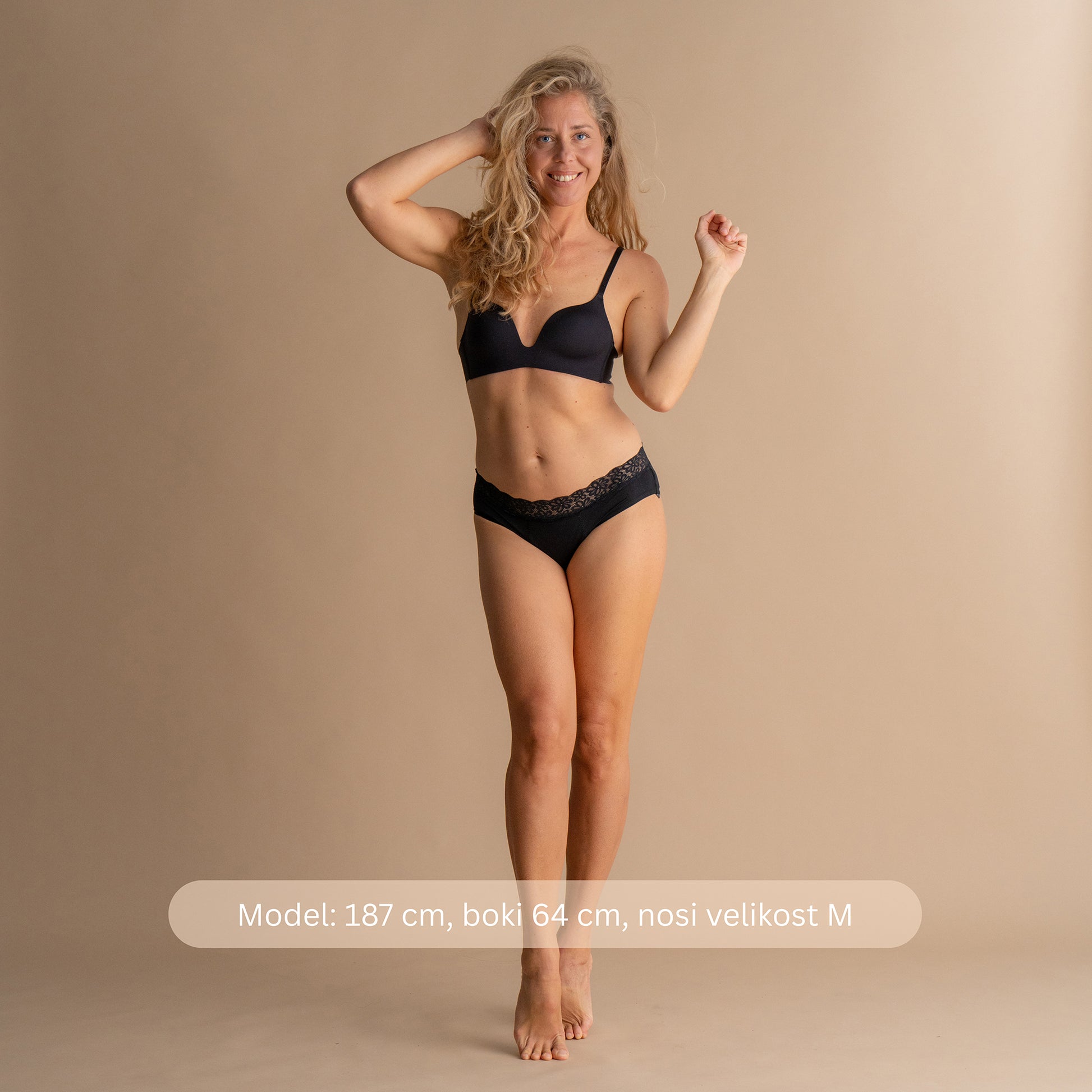 Vollkörperansicht enega modela, ki nosi Leakproof Soft Cotton Brief v črni barvi, z nežnim čipkastim dizajnom in udobnim prilegom. Model je visok 187 cm, ima obseg bokov 64 cm in nosi velikost M.